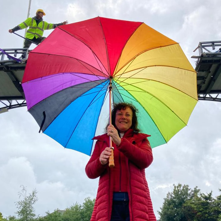 A massive rainbow coloured umbrella appears to patch up the gap between the bridge
